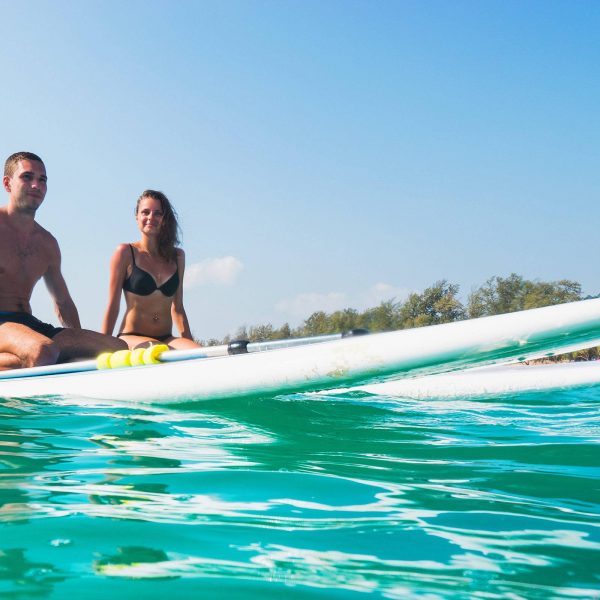 Couple Sitting Paddle Surfing . Beautiful Tropical Ocean, Active Beach Lifestyle.